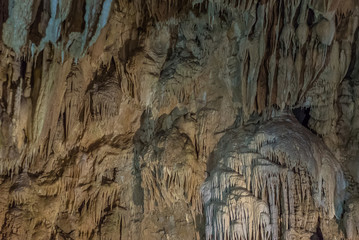 Under the ground. Beautiful view of stalactites and stalagmites in an underground cavern - New Athos Cave. Sacred ancient underworld formations.