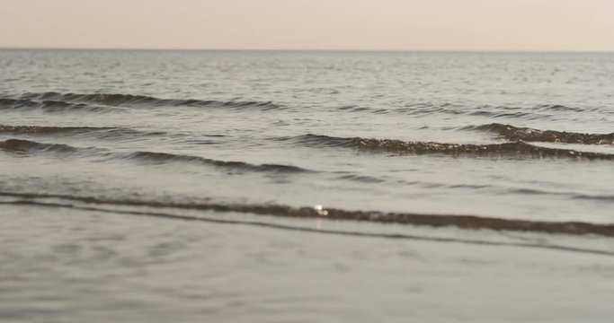 Slow motion closeup of small waves on a beach at sunset