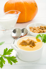 Pumpkin cream soup with croutons on white wooden table