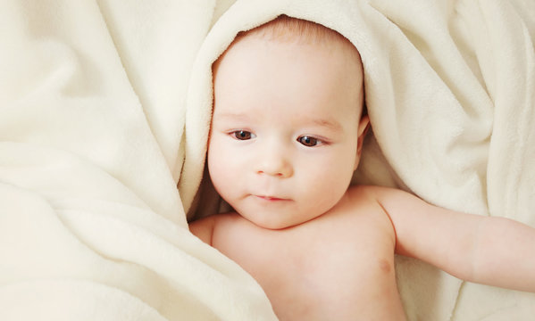cute baby lying in bed covered with soft blanket