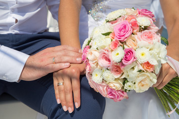 Hands of the newlyweds near the bouquet