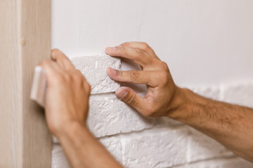 Professional Builder gluing decorative tile on wall.
