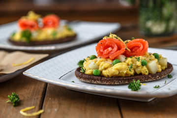 Smorrebrod with salmon and scramble egg on rye bread