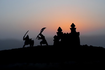 Medieval battle scene on sunset. Silhouettes of fighting warriors on sunset background.