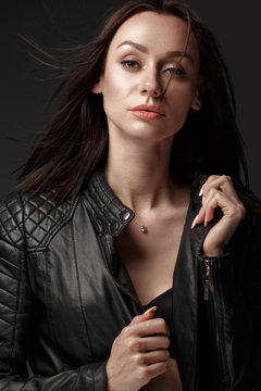 Daring girl model in black leather dress, style of rock, dark make up and beauty hair. Picture taken in the studio.