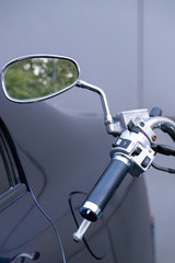 Motorcycle  parked next to the car. View of the dashboard and the steering wheel with rear-view mirrors.