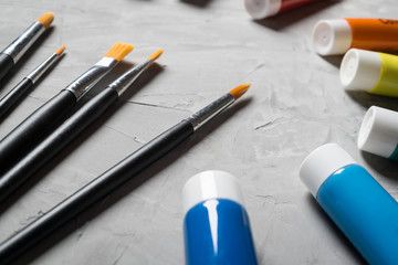 Painting brusches, white paper and watercolors on gray concrete background