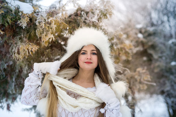 Woman in winter park posing in fur hat and scarf