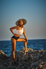 Young sexy woman with tanned skin in a swimsuit near the sea