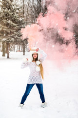 Beautiful woman in winter park holding red smoke bomb