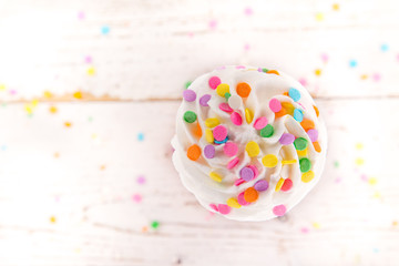 Colorful cup cake on wooden background.