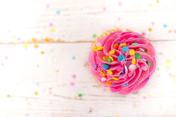 Colorful cup cake on wooden background.
