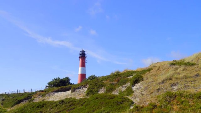 Wundersch&ouml;ner Leuchtturm H&ouml;rnum Sylt mit D&uuml;nen Landschaft  und blauen Himmel
