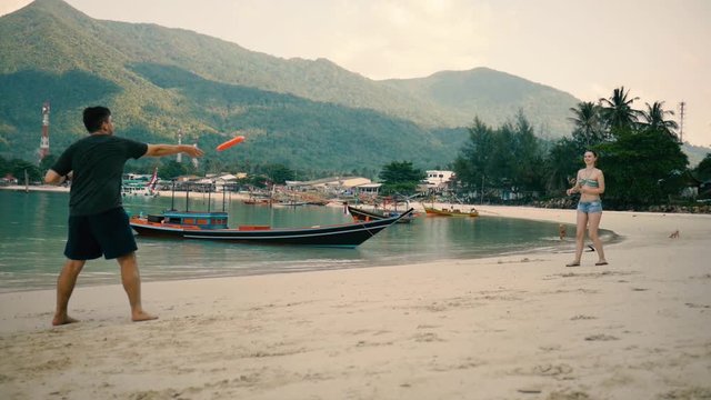 Couple playing on the beach in frisbee