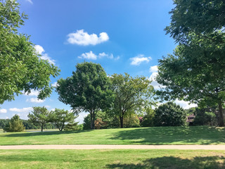 Beautiful grassy lawn park with trail pathway system near suburban residential houses in Coppell,...