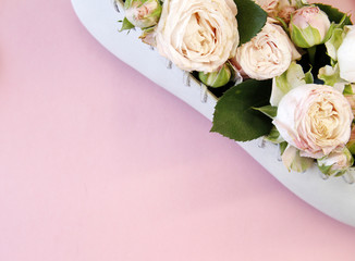 bouquet of small pink roses in a female shoe on a pink background