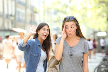 Teen greeting and friend ignoring her in the street - obrazy, fototapety, plakaty