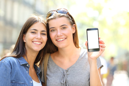 Two happy friends showing a smart phone screen