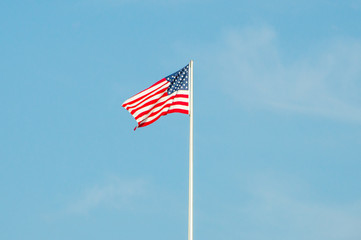 Waving USA flag on blue sky.