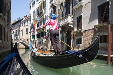 Fototapeta na wymiar Venice, Italy - May 21, 2017: The gondola floats along the old narrow street in Venice. Gondola is the most attractive tourist transport in Venice.