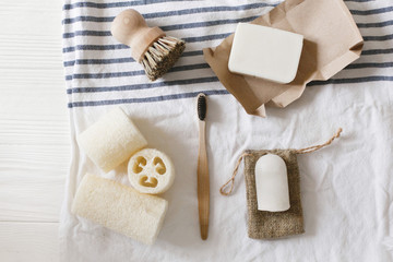 Fototapeta na wymiar zero waste concept. natural plastic free luffa, bamboo toothbrush, brush, coconut soap and crystal deodorant, for hygiene cleaning on towel, eco bathroom essentials. sustainable lifestyle