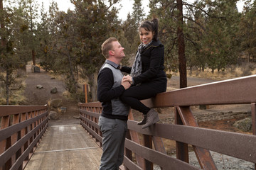Fototapeta premium Newlyweds smiling on a bridge holding hands