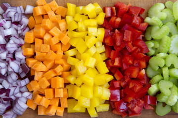 Chopped fresh vegetables (carrot, celery, red onion, peppers) arranged on cutting board, overhead...