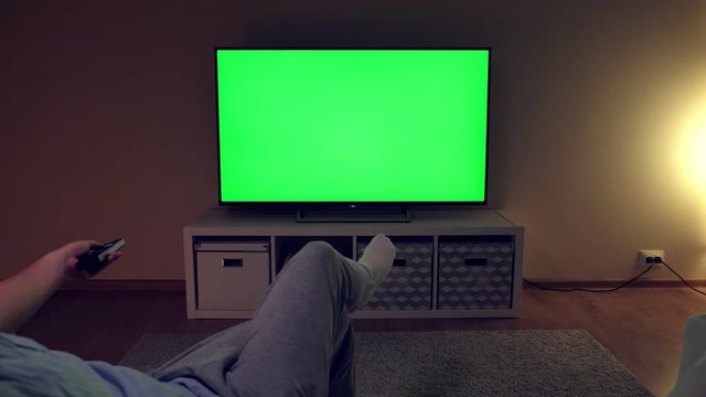 Watching tv with green screen at home interior. Evening