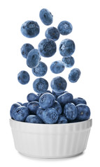 Fresh tasty blueberries falling into bowl on white background