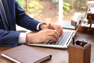 Lawyer working with laptop at table, focus on hands