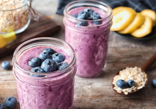 Jars with blueberry smoothies on table, closeup