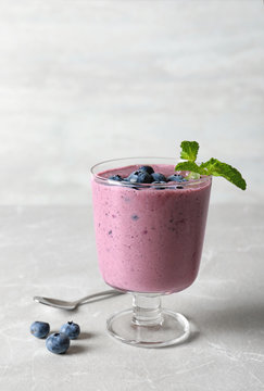 Glass with blueberry smoothie on grey table