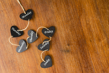 Heart of black wood with days of the weekend written on it.