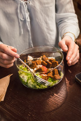 Woman's hands and a bowl of healthy green salad. Low key food photography, warm colors, toned image