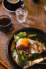 Avocado toast with egg and pomegrate seeds on black plate at restaurant table. Dark food photography concept. Copy space