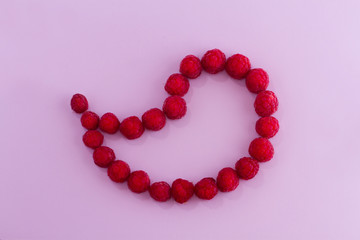 Group of berries raspberries spread in the form of a drop on a light purple background.