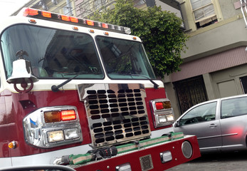 Front view of fire truck with flashing lights parked outside residential city apartment building.