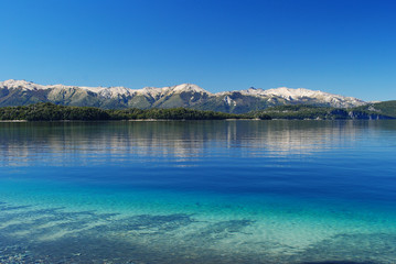 Beautiful landscape of Nahuel Huapi lake, in Villa la Angostura, Patagonia Argentina, with mountains in the background, blue sky, clear still water and the forest