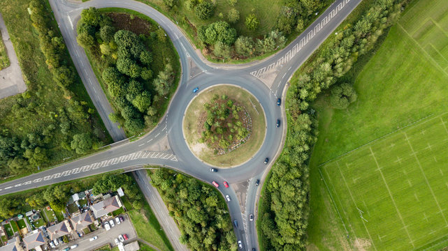 Top down aerial view of a traffic roundabout on a main road in an urban area of the UK