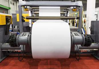 roll of white paper in modern paper cutting machine with control panel  ; industrial background ;mock up at paper