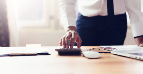 Business man in office and use computer and calculator to perform financial accounting. To plan advance budget.