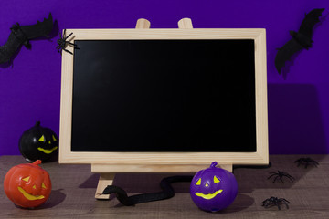 Halloween background concept. blackboard with decor pumpkin, bat, snake spider, on purple backdrop