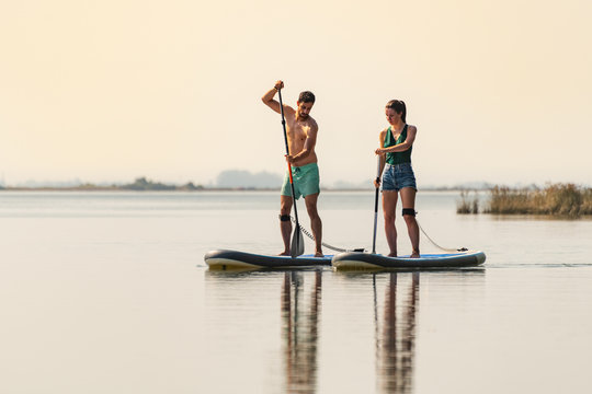 Man and woman stand up paddleboarding