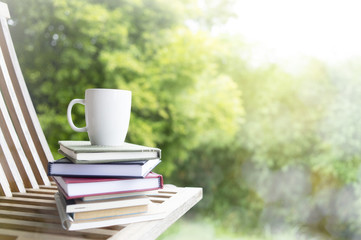 Composition with Stack of books and cup of coffee on blurred green background.