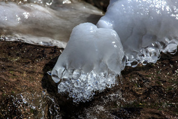 Abstract Macro, Naturally Formed  Organic Ice Sculpture, photograph of smooth transparent ice surface glistening in the sunshine. Water, Ice, Cold, Winter, melting in a natural river setting outside.