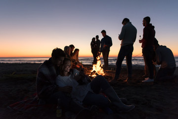 Couple enjoying bonfire with friends on beach