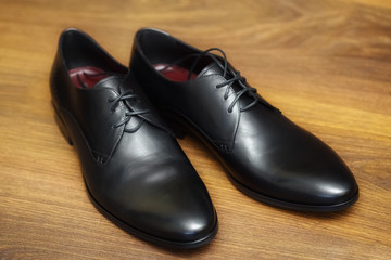 Black leather male shoes on wooden background