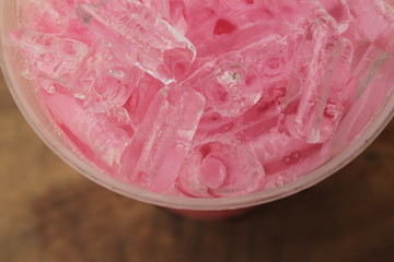 Closeup top view ice of strawberry sweet milk pink in takeaway cup.