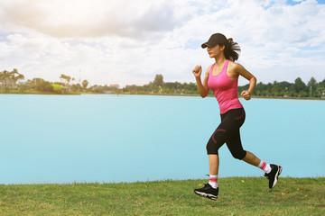 Sporty female jogger morning exercise on seaside on grass.