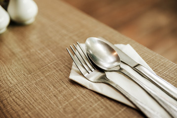 fork, spoon and knife with white paper on the old wood table For breakfast.